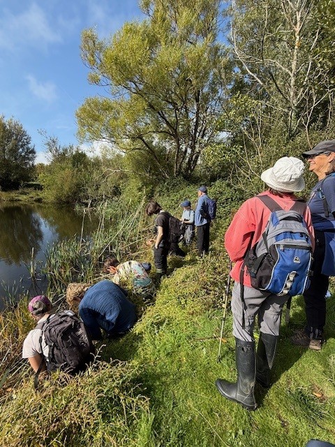 A group of adults standing by a river bank
