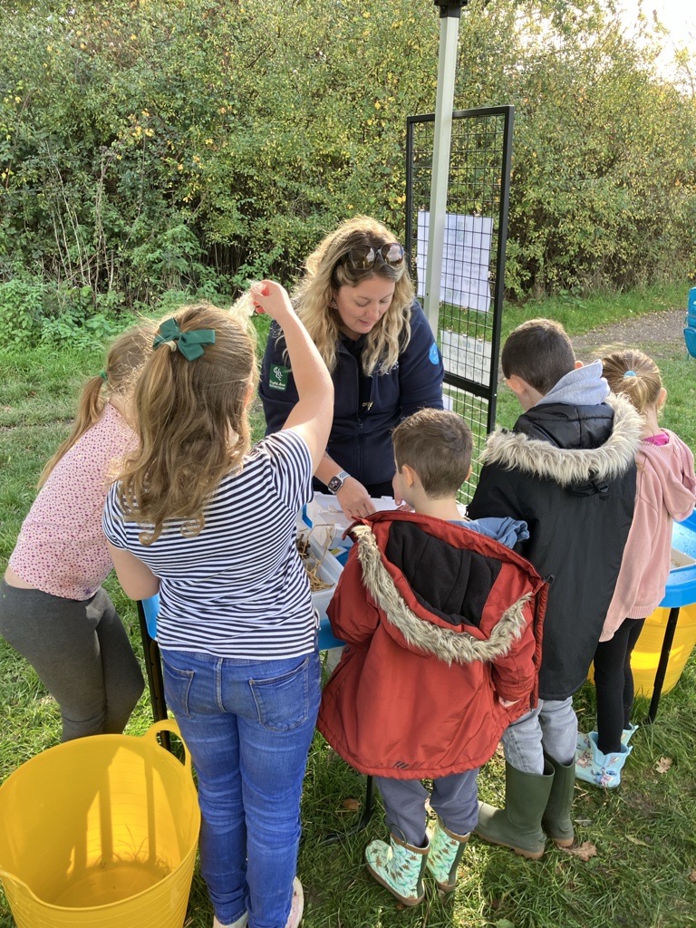 A group of children gathering around an adult outdoors.